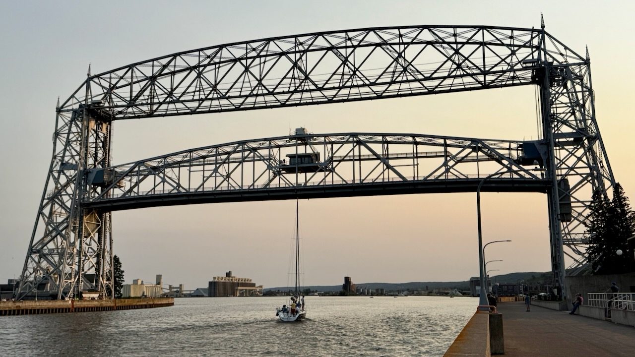 The Aerial Lift Bridge in Duluth, Minnesota, with a sailboat passing beneath at sunset